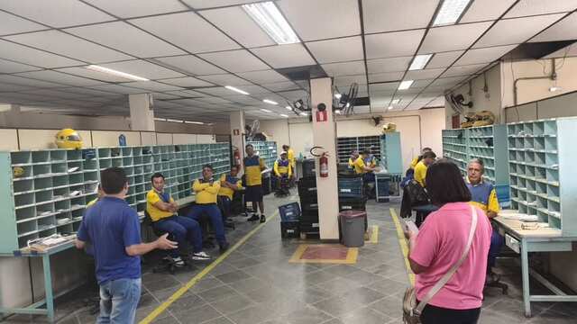 Trabalhadores reunidos no setor de triagem durante visita da diretoria